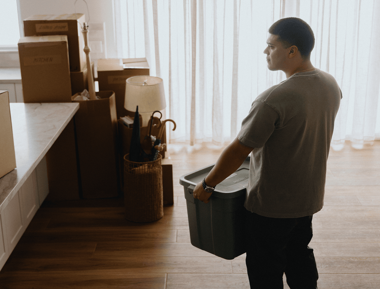 person carrying a box into an empty room of their new home