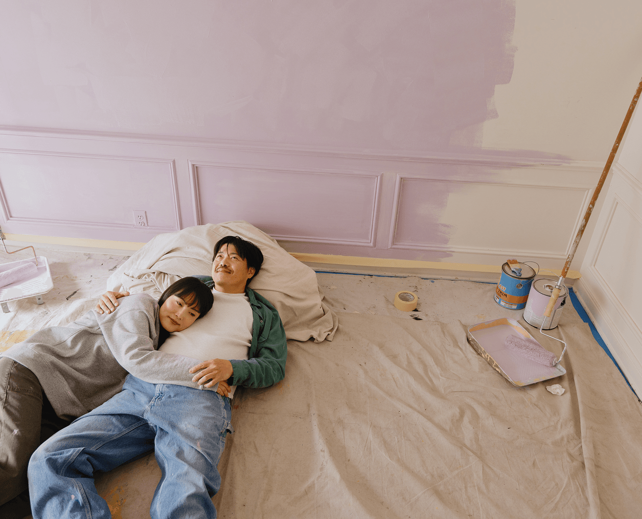 couple laying down in a freshly painted room, admiring their work