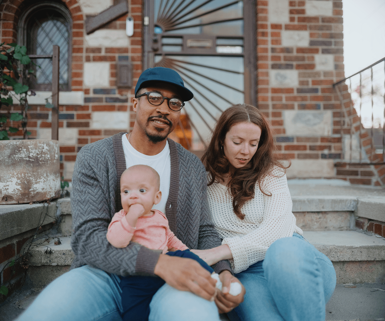 family sitting on step in front of house