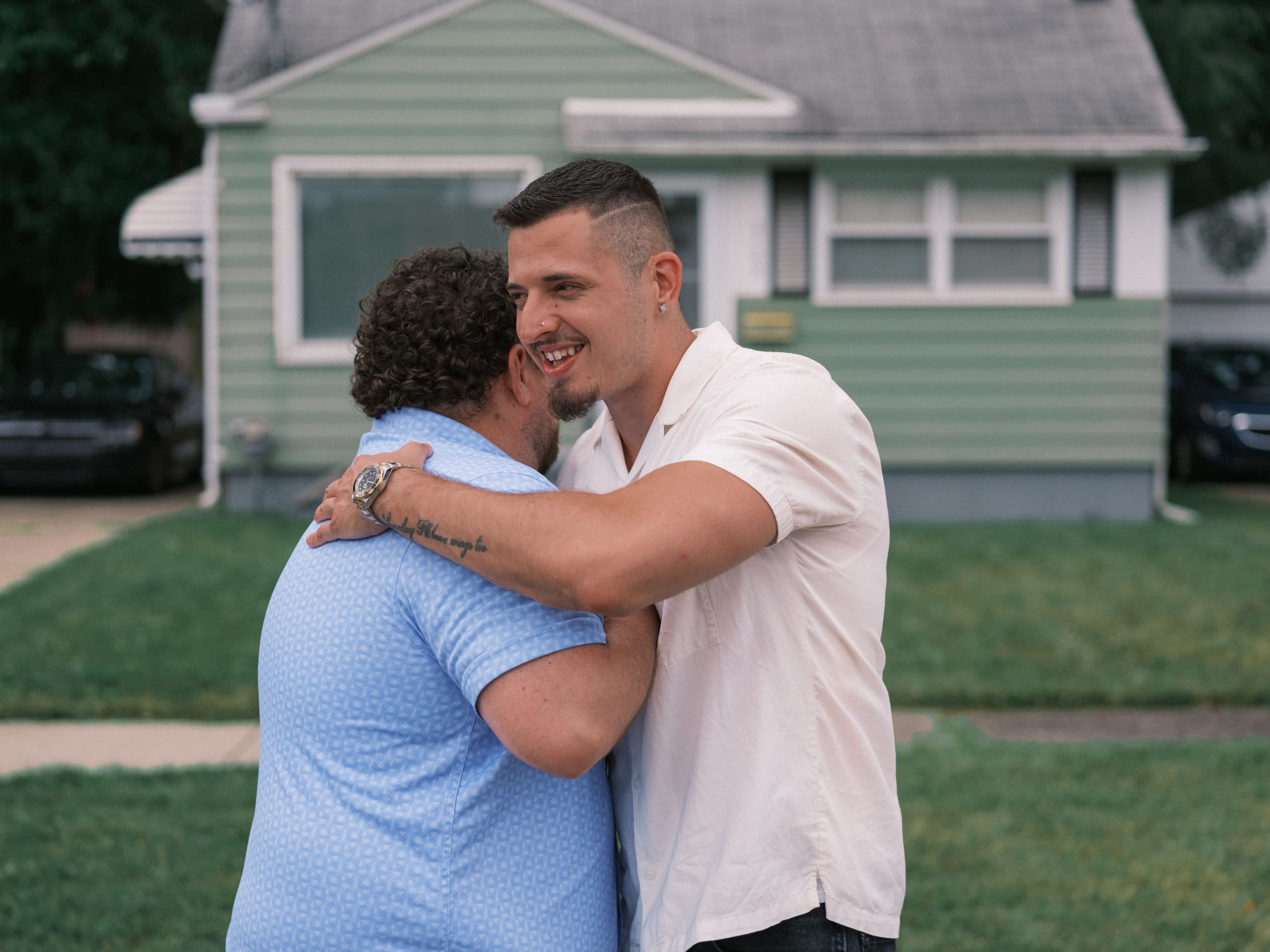 Two people hugging in front of home