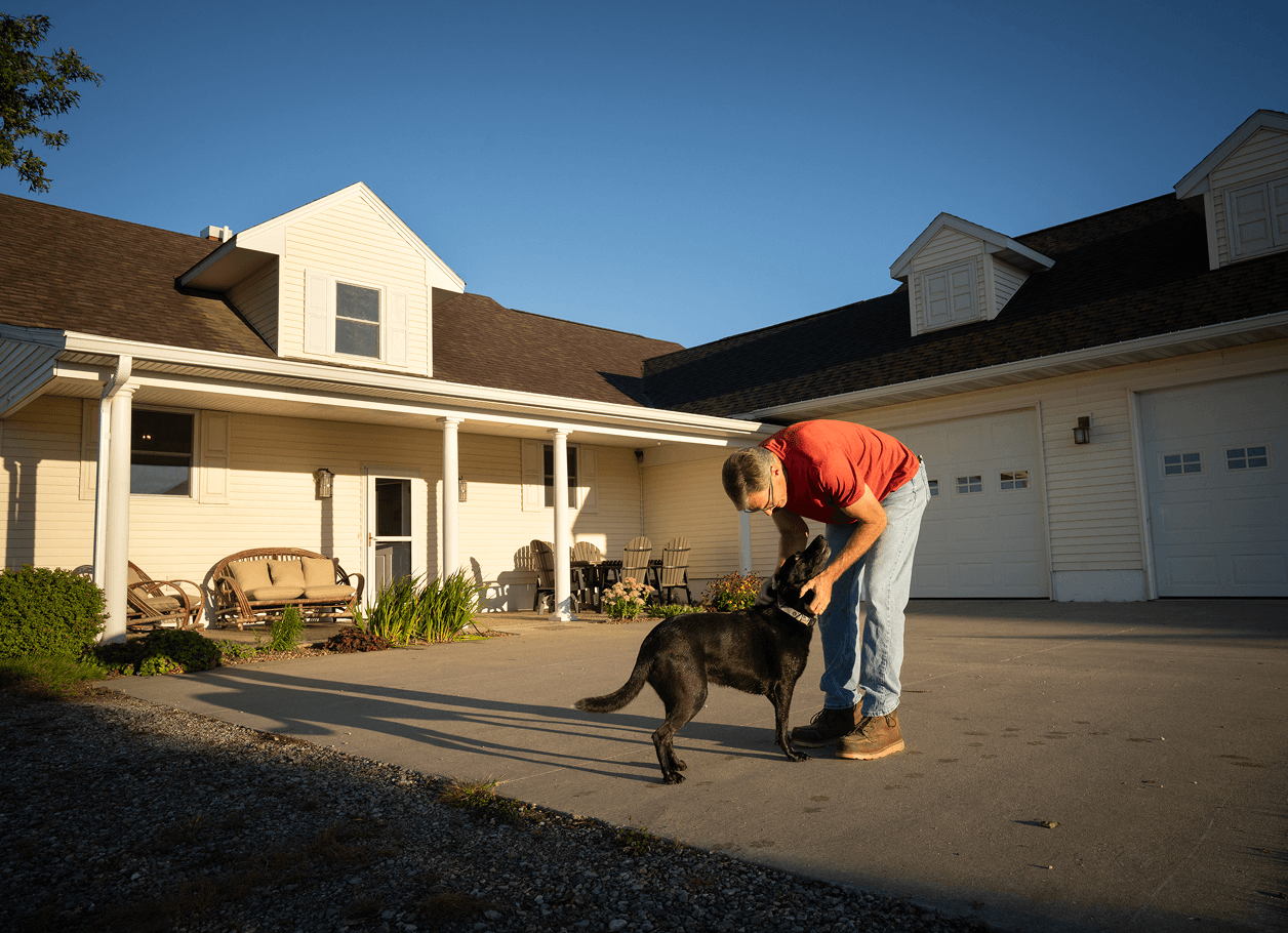 person petting their dog in front of their home