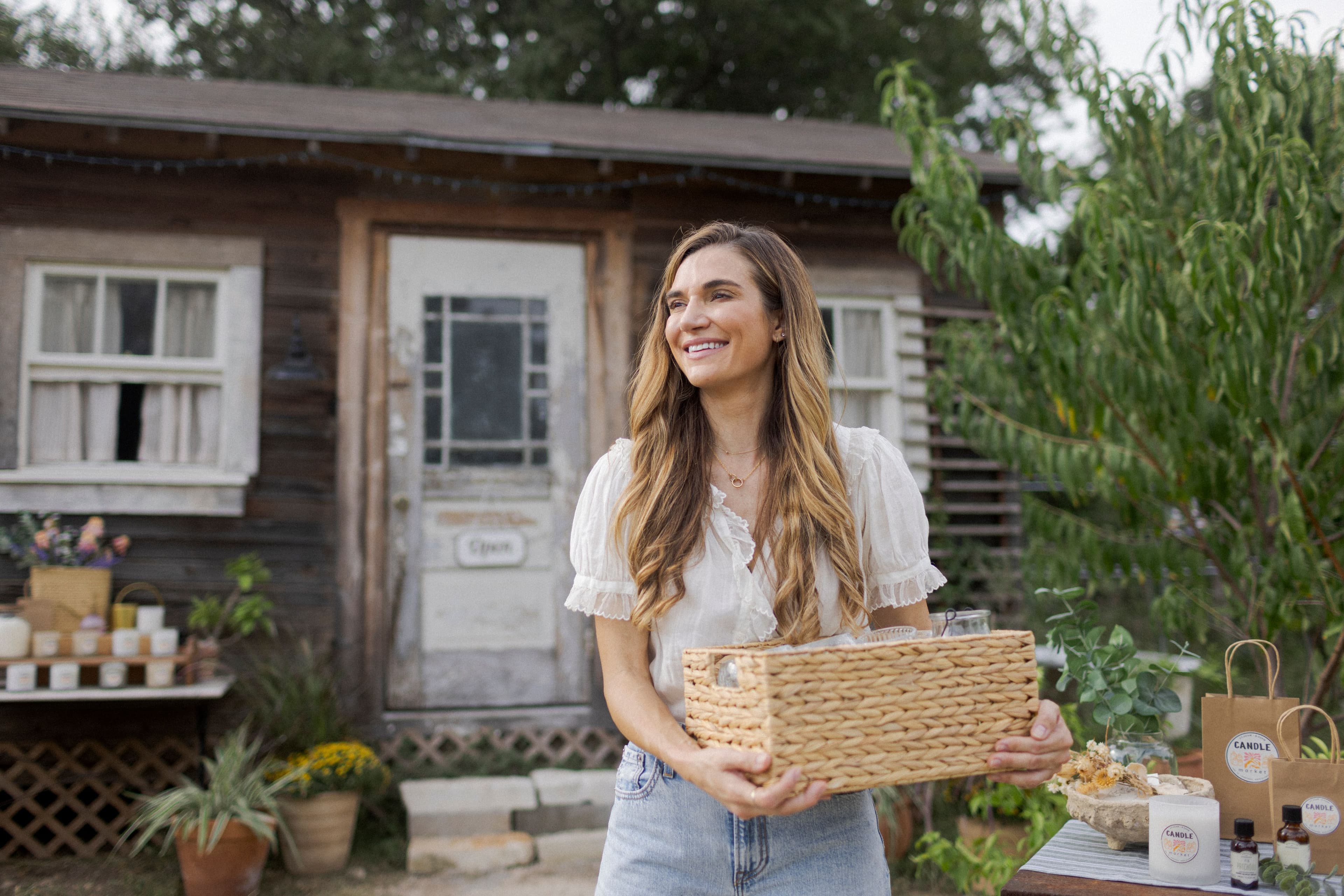 Person holding a basket of drinking glasses in front of home